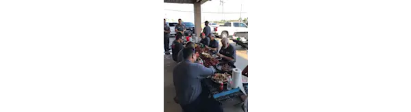 People gather in a pavilion eating lunch at a table